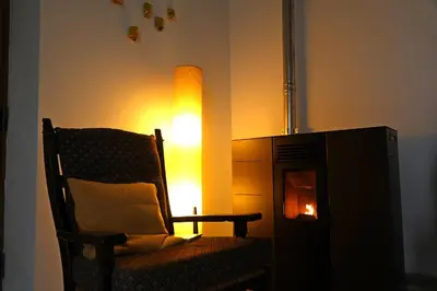 a living room with a chair and a fire place at Bakkershuisje Kraneveldhoeve in Haacht