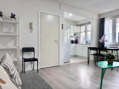 a white living room with a table and a kitchen at Breughel Apartments in Antwerp
