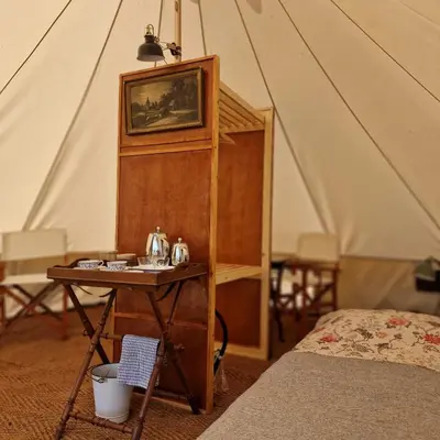 a room with a bed and a table in a tent at Strackxhoeve Veldtent 'Veldslaap' in Laakdal
