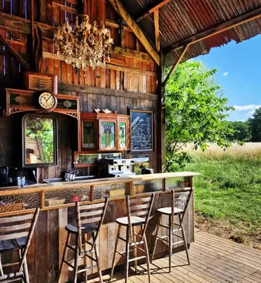 a kitchen with a bar with chairs and a clock at Strackxhoeve Veldtent 'Veldslaap' in Laakdal