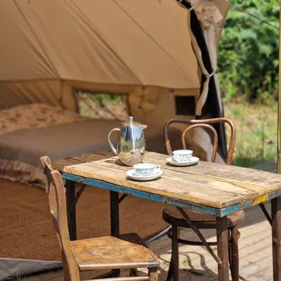 a wooden table with a tea pot and two chairs at Strackxhoeve Veldtent 'Veldslaap' in Laakdal