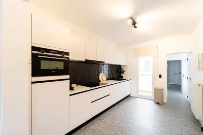 a kitchen with white cabinets and a black appliance at Family-Friendly 2-Bedroom Apartment in Antwerp in Antwerp