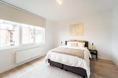 a white bedroom with a bed and a window at Family-Friendly 2-Bedroom Apartment in Antwerp in Antwerp