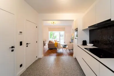 a kitchen with white cabinets and a living room at Family-Friendly 2-Bedroom Apartment in Antwerp in Antwerp