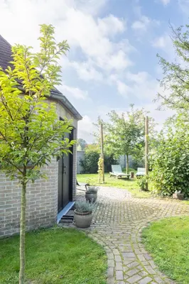 a brick house with a door and a tree at Octagoon in Tessenderlo
