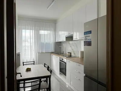 a kitchen with white cabinets and a table and a table and chairs at MiMi in Brussels