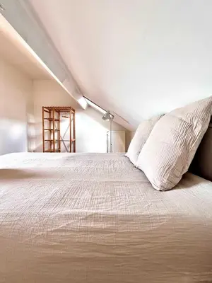 a bedroom with a large bed with white sheets at Cosy haven in Aalst with terrace a green haven in Aalst