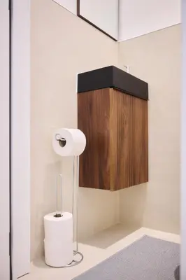 a bathroom with a toilet paper dispenser and a wooden cabinet at Apartment Forest Center 2 in Brussels