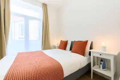 a bedroom with a bed with orange pillows and a window at Apartment Forest Center 2 in Brussels