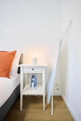 a white bedside table with a blue alarm clock on it at Apartment Wiels 3 in Brussels