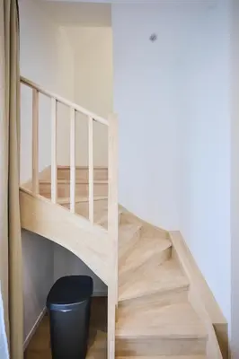 a wooden staircase in a room with a black trash can at Apartment Berthelot 5 in Brussels