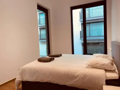 a bedroom with a large bed with two windows at The Diplomatic Apartment in Brussels