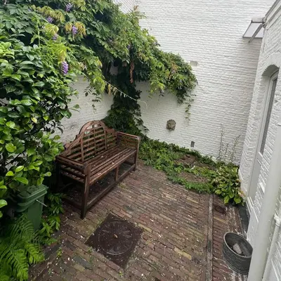 a wooden bench sitting on a brick patio at Denderhuis in Dendermonde