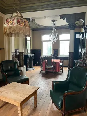 a living room with chairs and a table and a chandelier at Denderhuis in Dendermonde