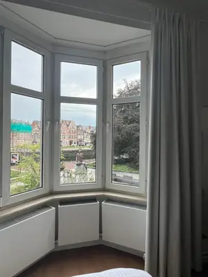 a room with three windows and a bed at Denderhuis in Dendermonde