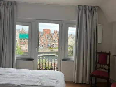 a bedroom with two windows and a bed and a chair at Denderhuis in Dendermonde