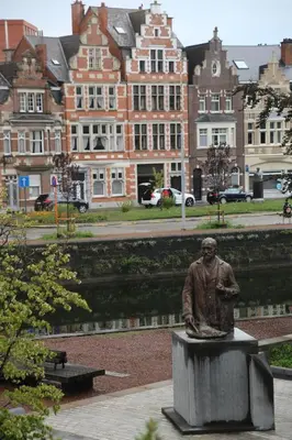 a statue of a man sitting on a bench at Denderhuis in Dendermonde