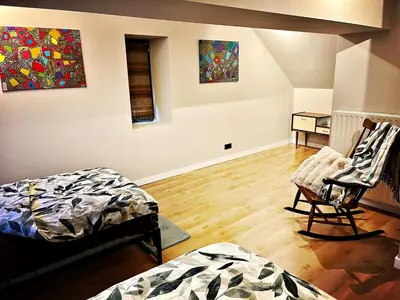a room with two beds and a chair and paintings at De Zweverik in Dessel