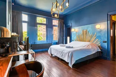 a bedroom with a bed and a blue wall at Boutique Cogels Osy in Antwerp