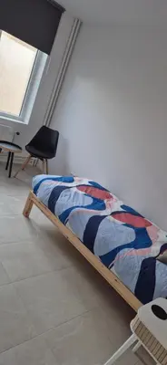 a bed in a room with a chair and a window at Cosy flat in Antwerp