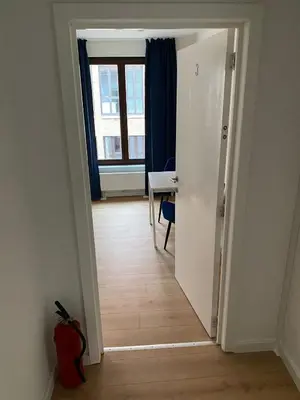 a hallway with a room with a table and a window at Grote Markt suite 3 in Antwerp