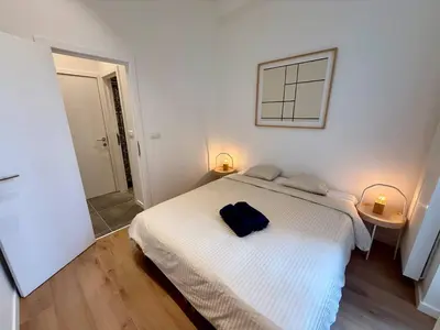 a bedroom with a white bed with a blue bag on it at The Modern Nest - Jourdan in Brussels
