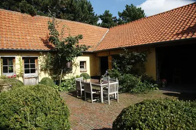 a house with a table and chairs in the yard at Vakantie Appartement De Sneppelhoeve in Wuustwezel