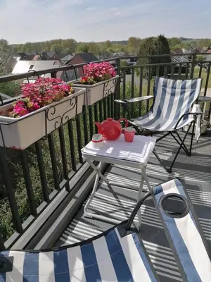 a chair and a table on a balcony with flowers at Meerdael Refuge Appartement in Oud-Heverlee