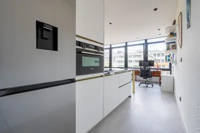 a kitchen with white cabinets and a desk at Ecstatic Living Ixelles, Luxury in the European Quarter in Brussels