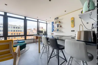 a kitchen with white chairs and a counter with a large window at Ecstatic Living Ixelles, Luxury in the European Quarter in Brussels