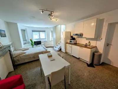 a living room with a bed and a kitchen with a table at Central and convenient studio near supermarkets and public transports in Brussels