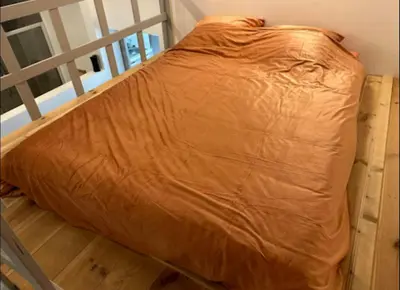a bed with an orange comforter on top of it at Antwerp West Side ,airco in Zwijndrecht