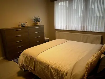 a bedroom with a bed and a dresser and a window at Modern 2-Bed Urban Apartment in Brussels