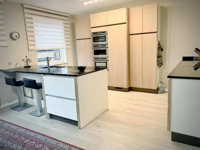 a kitchen with white cabinets and a kitchen island at Modern 2-Bed Urban Apartment in Brussels