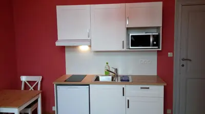a kitchen with white cabinets and a sink and a microwave at Charming studio apartment with terrace near Mérode in Brussels