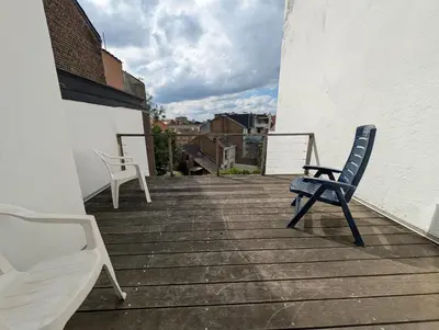 a blue chair sitting on a balcony with a view at Charming studio apartment with terrace near Mérode in Brussels