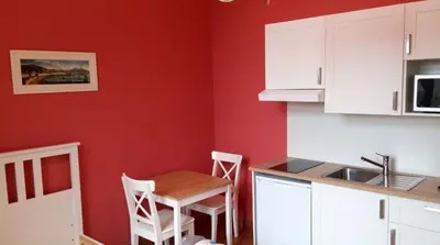 a kitchen with red walls and a small table and chairs at Charming studio apartment with terrace near Mérode in Brussels