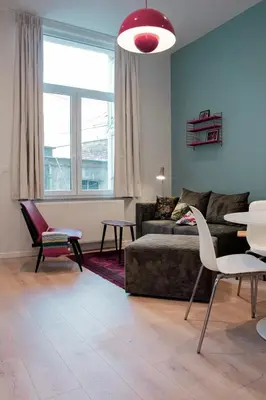 a living room with a couch and a table and chairs at Chaleureux appartement aux Marolles in Brussels