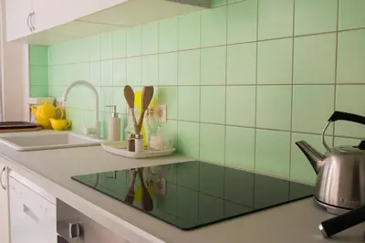 a kitchen with green tile walls and a counter with a sink at Chaleureux appartement aux Marolles in Brussels