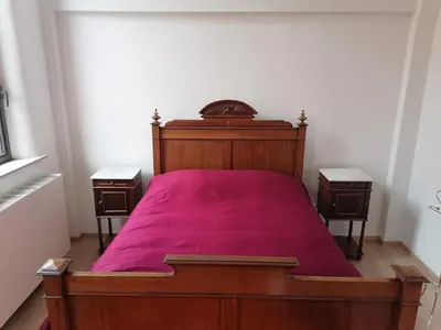 a bedroom with a wooden bed with a red blanket at Unique renovated chapel in Temse