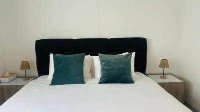 a bed with white sheets and green pillows at Villa-gey Escape in Bekkevoort