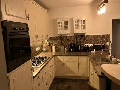 a kitchen with white cabinets and a stove top oven at The Oak & Squirrel Villa in Hoogstraten