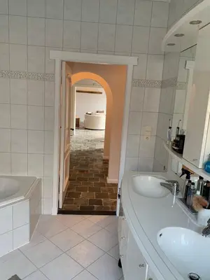 a bathroom with two sinks and a tub and a hallway at The Oak & Squirrel Villa in Hoogstraten