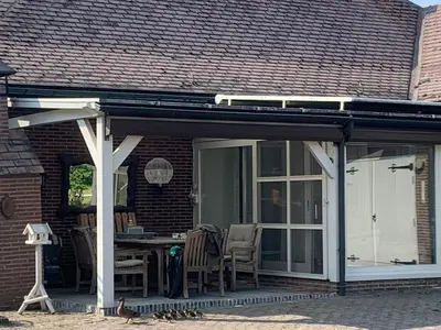a pavilion with a table and chairs on a house at The Oak & Squirrel Villa in Hoogstraten