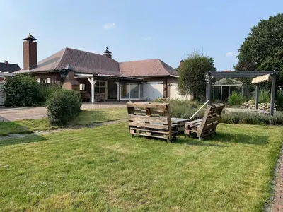 two wooden benches sitting in the grass in front of a house at The Oak & Squirrel Villa in Hoogstraten