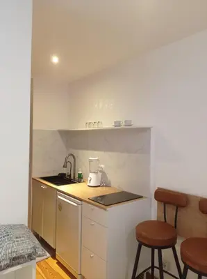 a small kitchen with a sink and two bar stools at Cozy and centrally located studio apartment in Brussels
