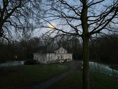 an old house sitting in the middle of a field at Logies Het Koetshuis in Herentals