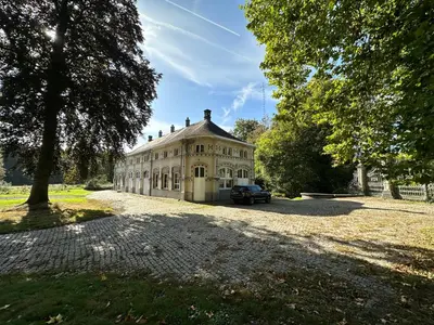 an old house with a car parked in the driveway at Logies Het Koetshuis in Herentals