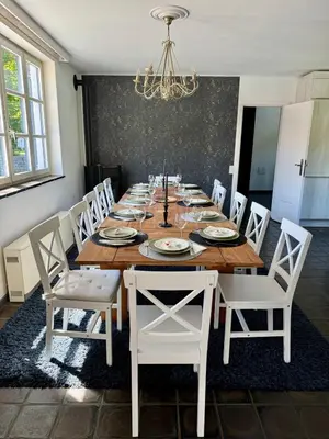 a dining room table with white chairs and a chandelier at La Chanterelle in Wavre