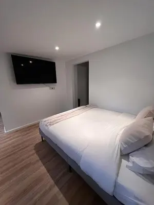 a bedroom with a white bed with a flat screen tv at Studio in Brussels in Brussels